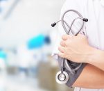 Doctor with a stethoscope in the hands and hospital background.